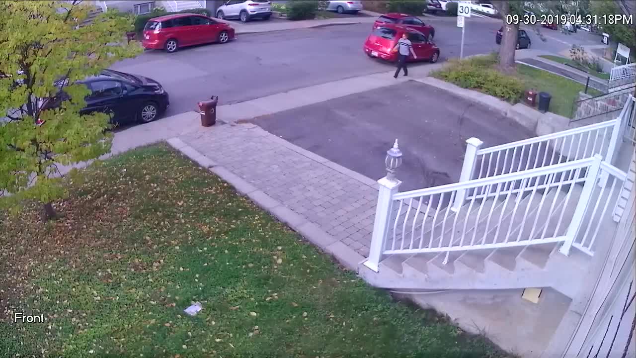 Une femme jette une poubelle sur une voiture