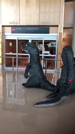 Deux enfants déguisés en dinosaure accueillent leur grand-mère à l'aéroport mais elle a aussi prévu une petite surprise