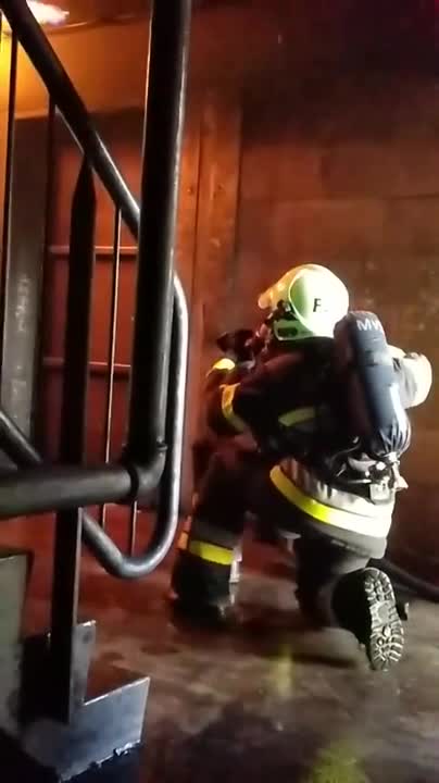 Deux pompiers font un bouclier d'eau pour se protéger d'un retour de flammes