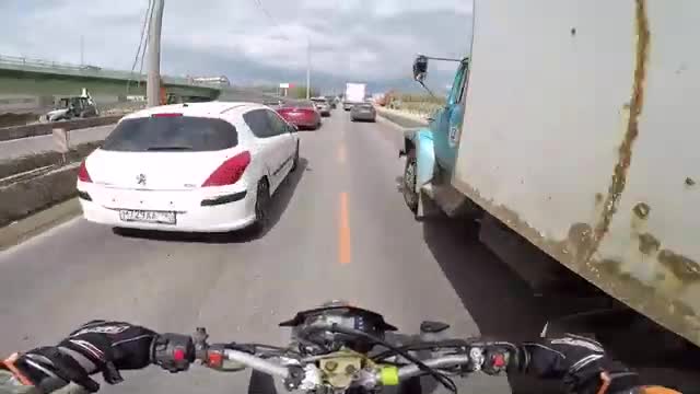 Un motard double un camion dans les bouchons