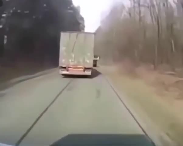 Un camion balance un tracteur sur le bord de la route