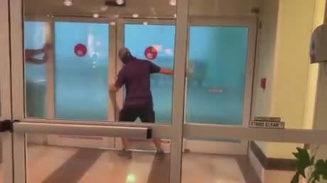 Deux hommes tiennent une porte coulissante pendant une tempête (Floride)
