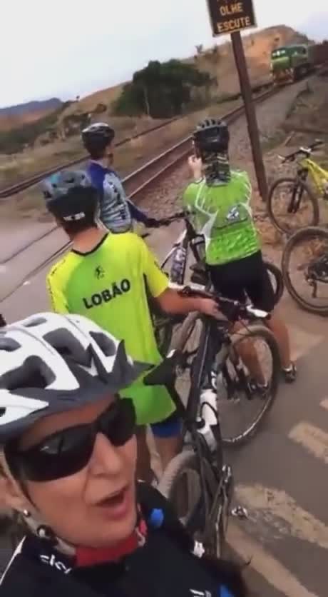 Des cyclistes s'arrêtent pour saluer un train