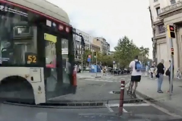 Un homme en trottinette grille un feu tricolore, devant un bus