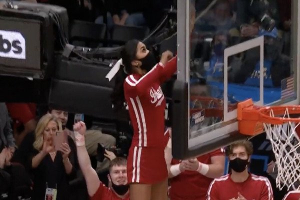 Une cheerleader récupère un ballon de basket coincé sur un panier