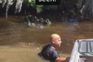 Un homme se baigne dans une rivière et soulève un alligator