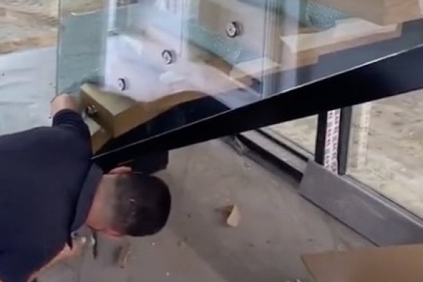 Un homme utilise un marteau sous un escalier vitré