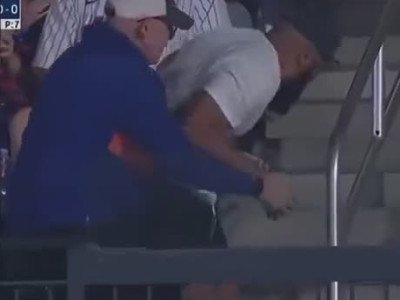 Deux hommes se battent pour une balle dans un stade de baseball